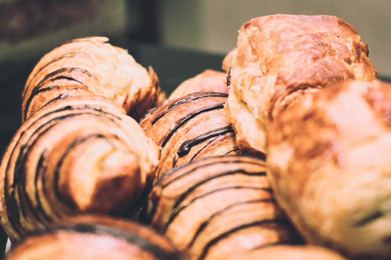Delicious freshly baked pastries with chocolate drizzle, showcasing a sweet indulgence.